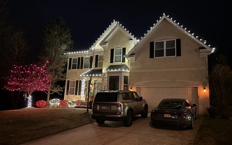 Steep gables outlined in warm white above a lit driveway