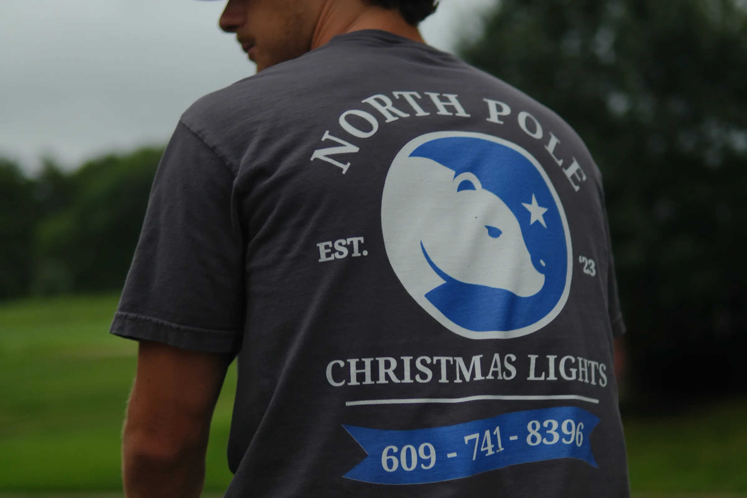 The North Pole bear mark across the back of an installer's shirt, with EST '23 and the phone number