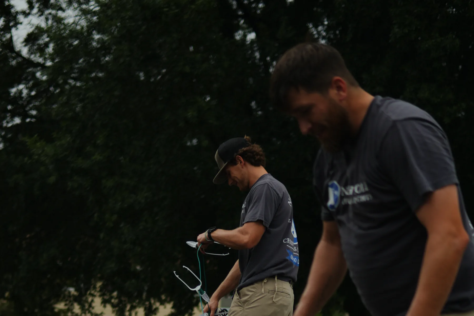 Two North Pole installers moving along a roof with a coil of lights